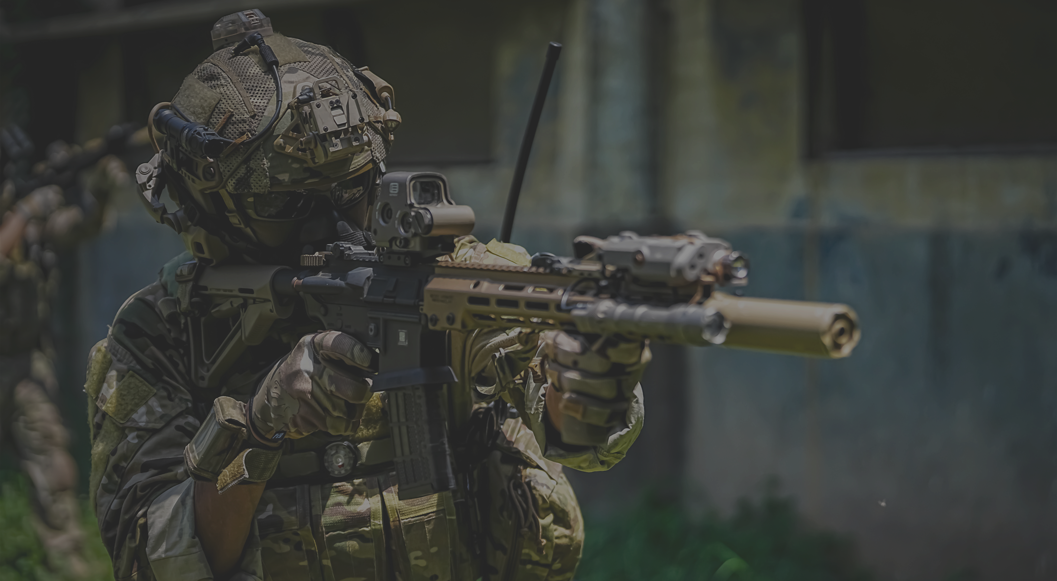 Person in military gear holding a rifle with a blurred background