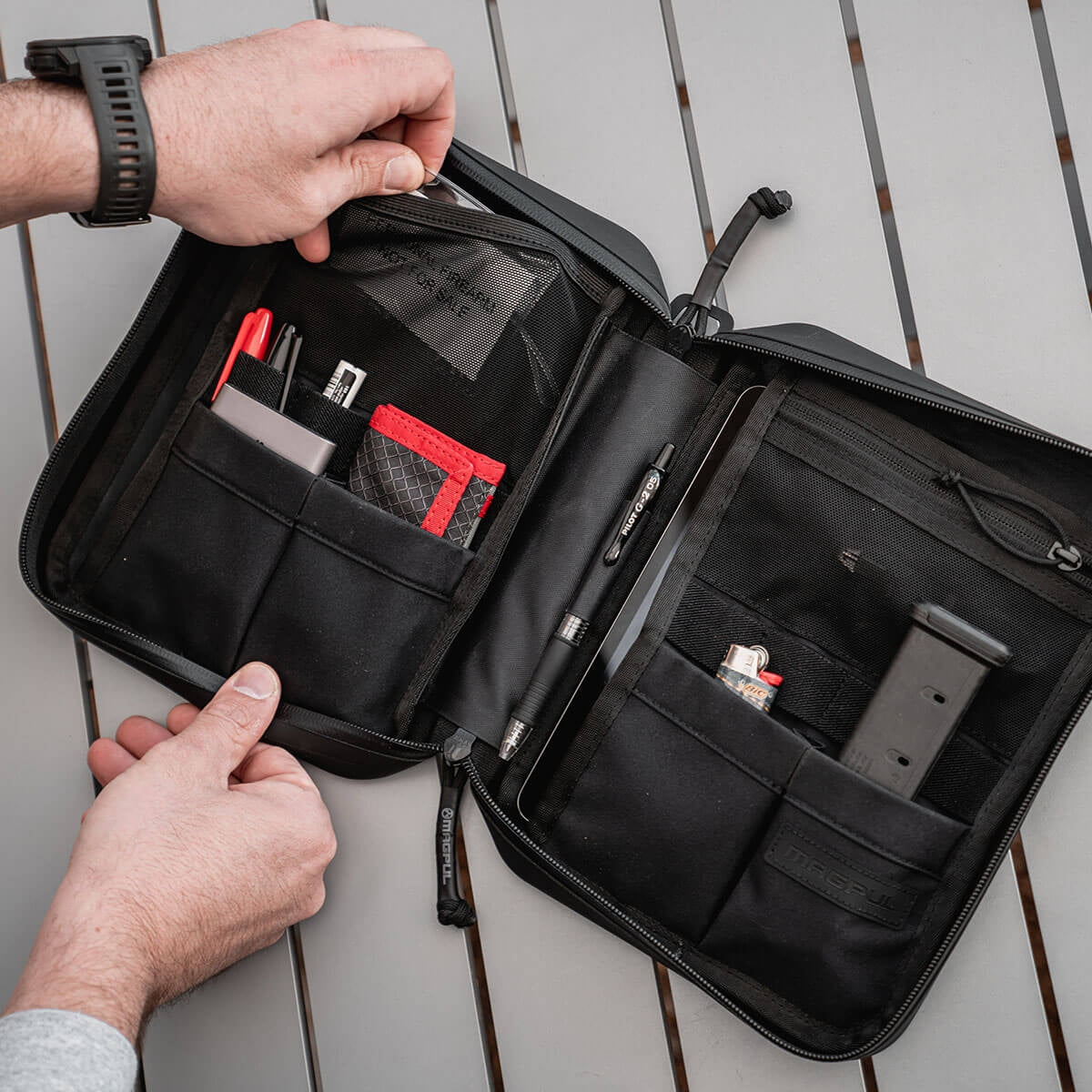 Black travel DAKA organizer with compartments on a wooden surface
