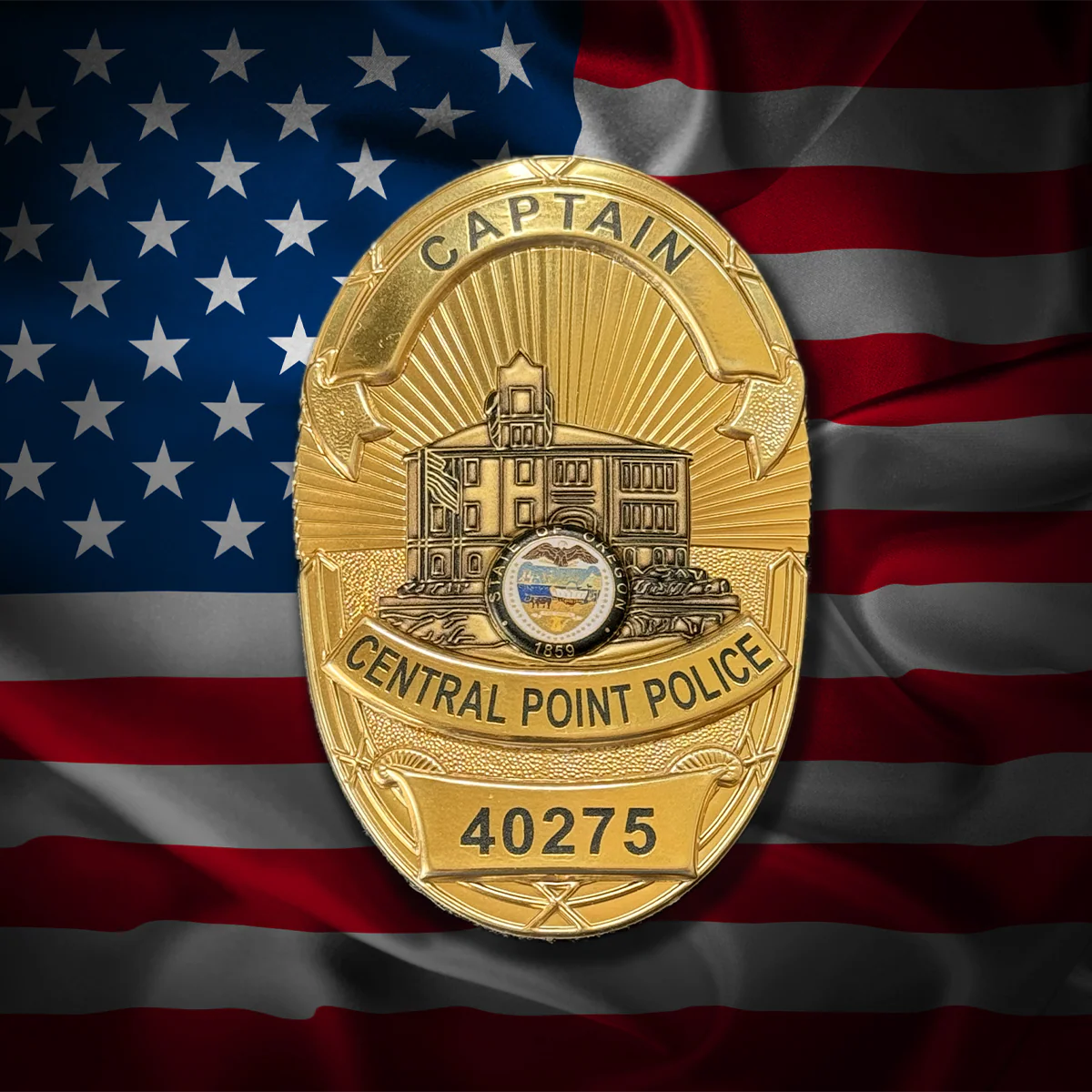 Gold police flex badge with 'Captain' and 'Central Point Police' text on an American flag background