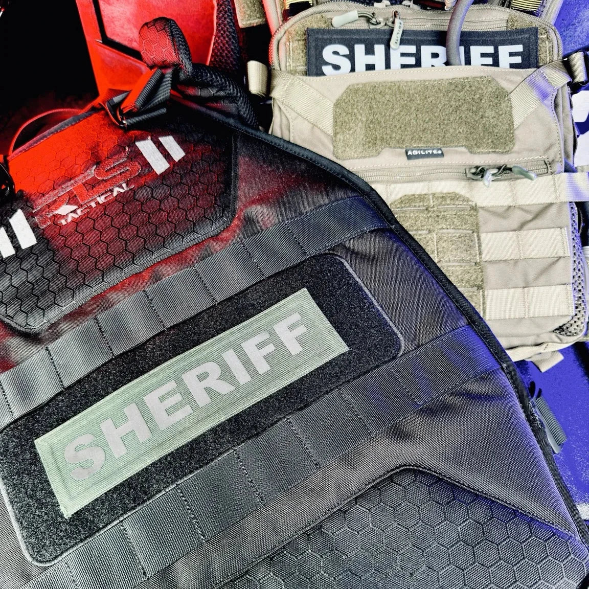 Close-up of a tactical vest with 'SHERIFF' patches on a blurred background
