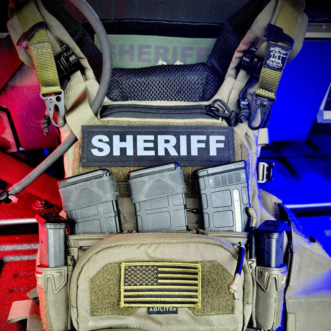 Molle tactical vest with 'Sheriff' patch and American flag emblem on a colorful background