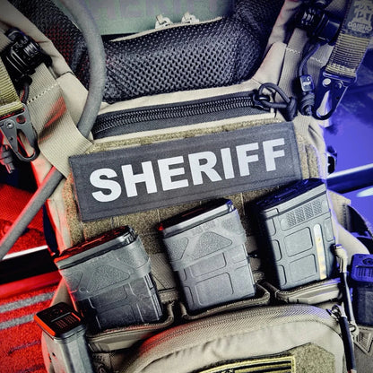 Law enforcement gear with 'SHERIFF' patch and American flag on a vehicle interior.