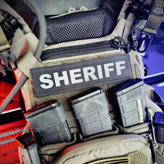 Law enforcement gear with 'SHERIFF' patch and American flag on a vehicle interior.
