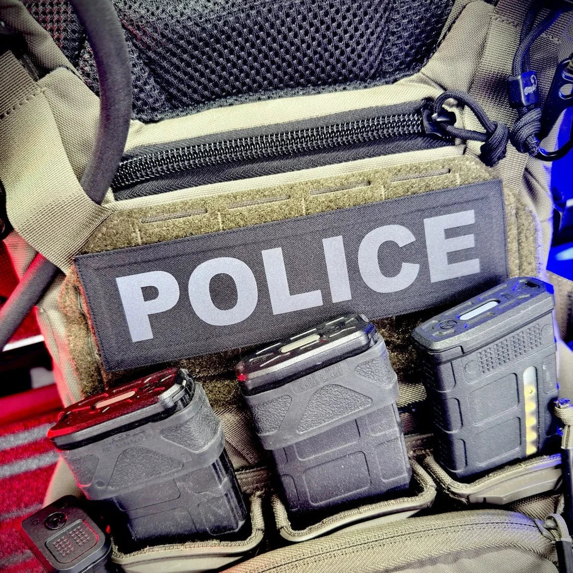 Molle pouch with 'POLICE' patch and various equipment on a tactical vest.