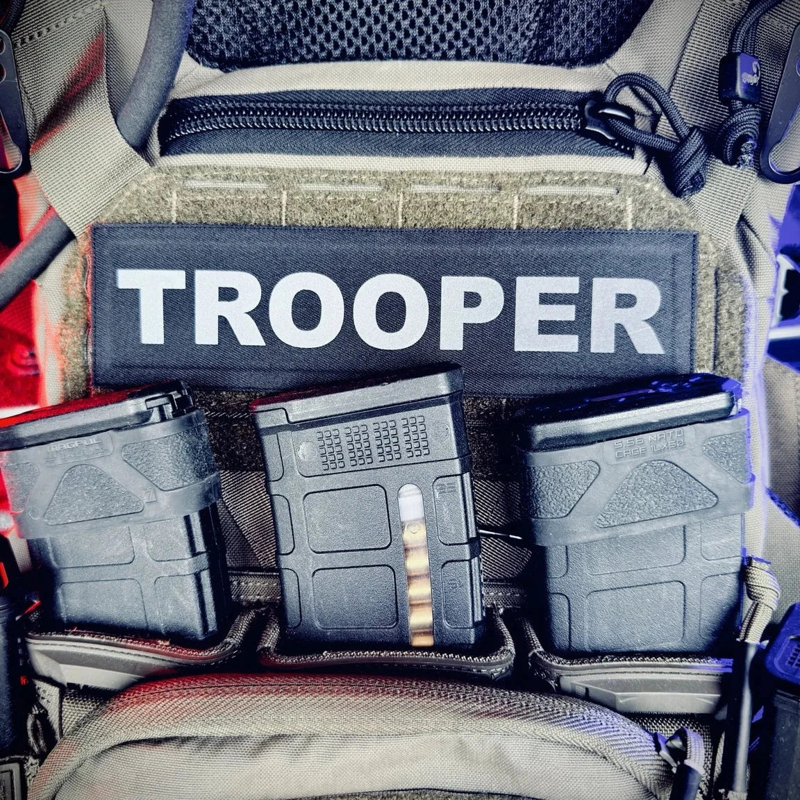Molle pouch with 'TROOPER' patch and magazines inside a vehicle.