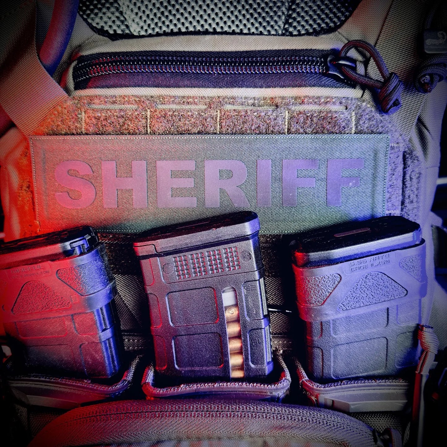 Three ammunition magazines in front of a bag labeled 'Sheriff'.