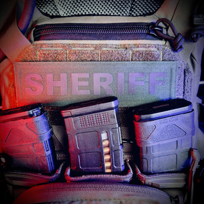 Three ammunition magazines in front of a bag labeled 'Sheriff'.