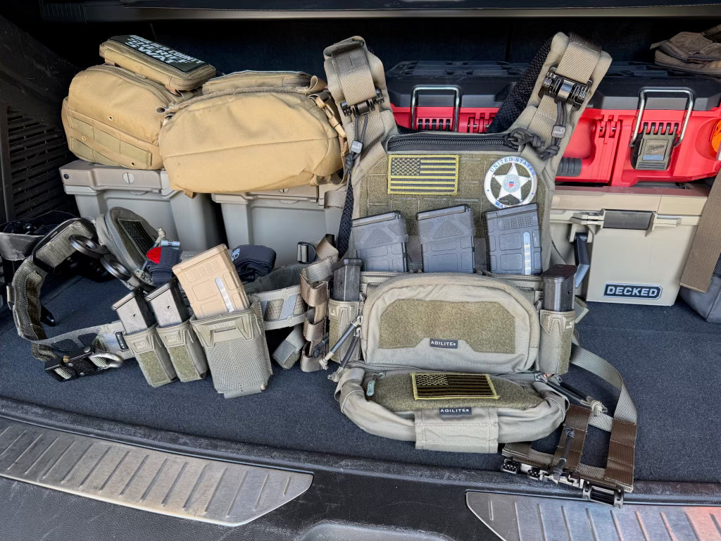 Tactical gear including vests and equipment in a vehicle's cargo area.