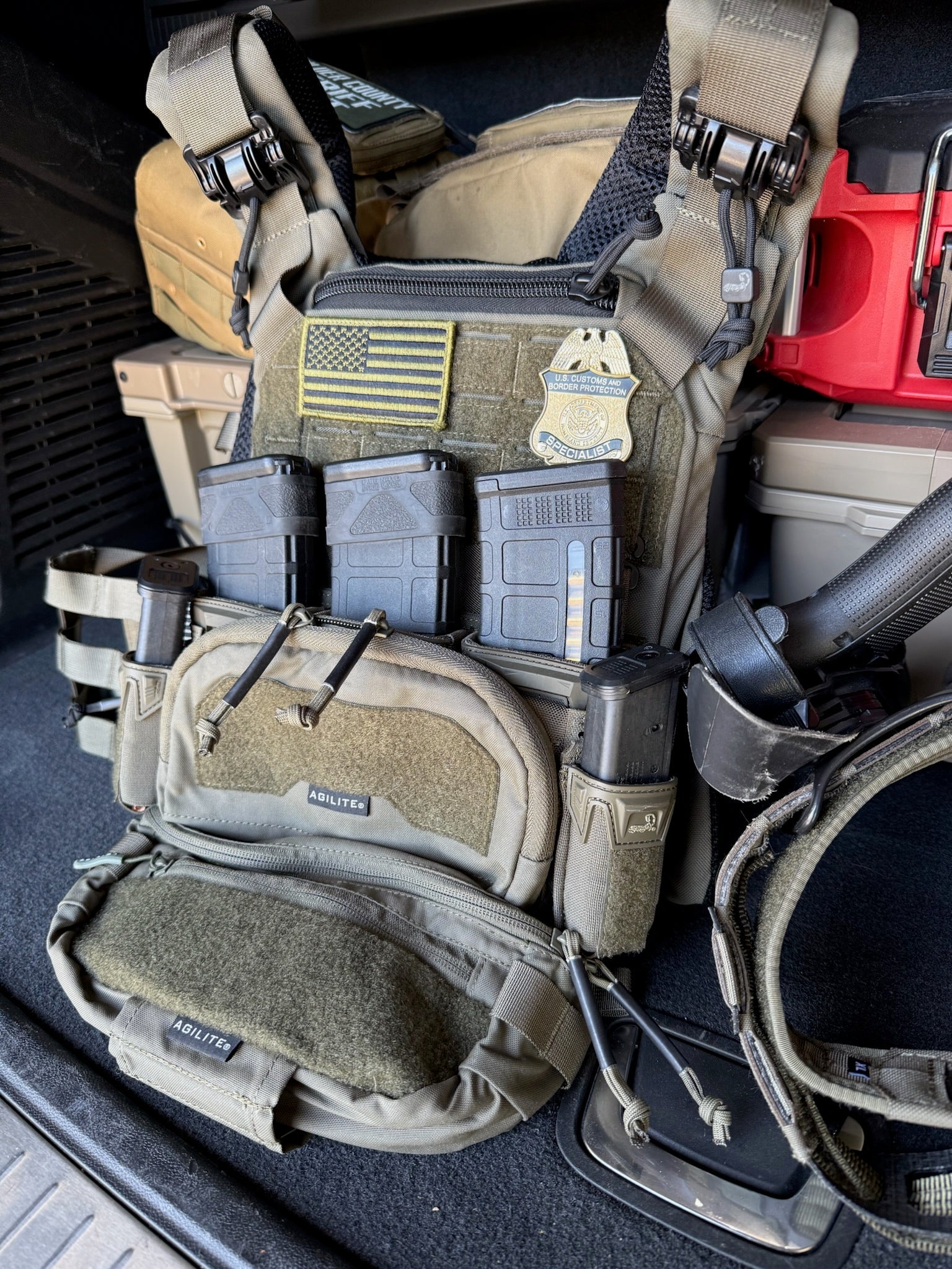  tactical vest with various pouches and equipment on a vehicle seat showing a CBP Specialist Flex Badge 