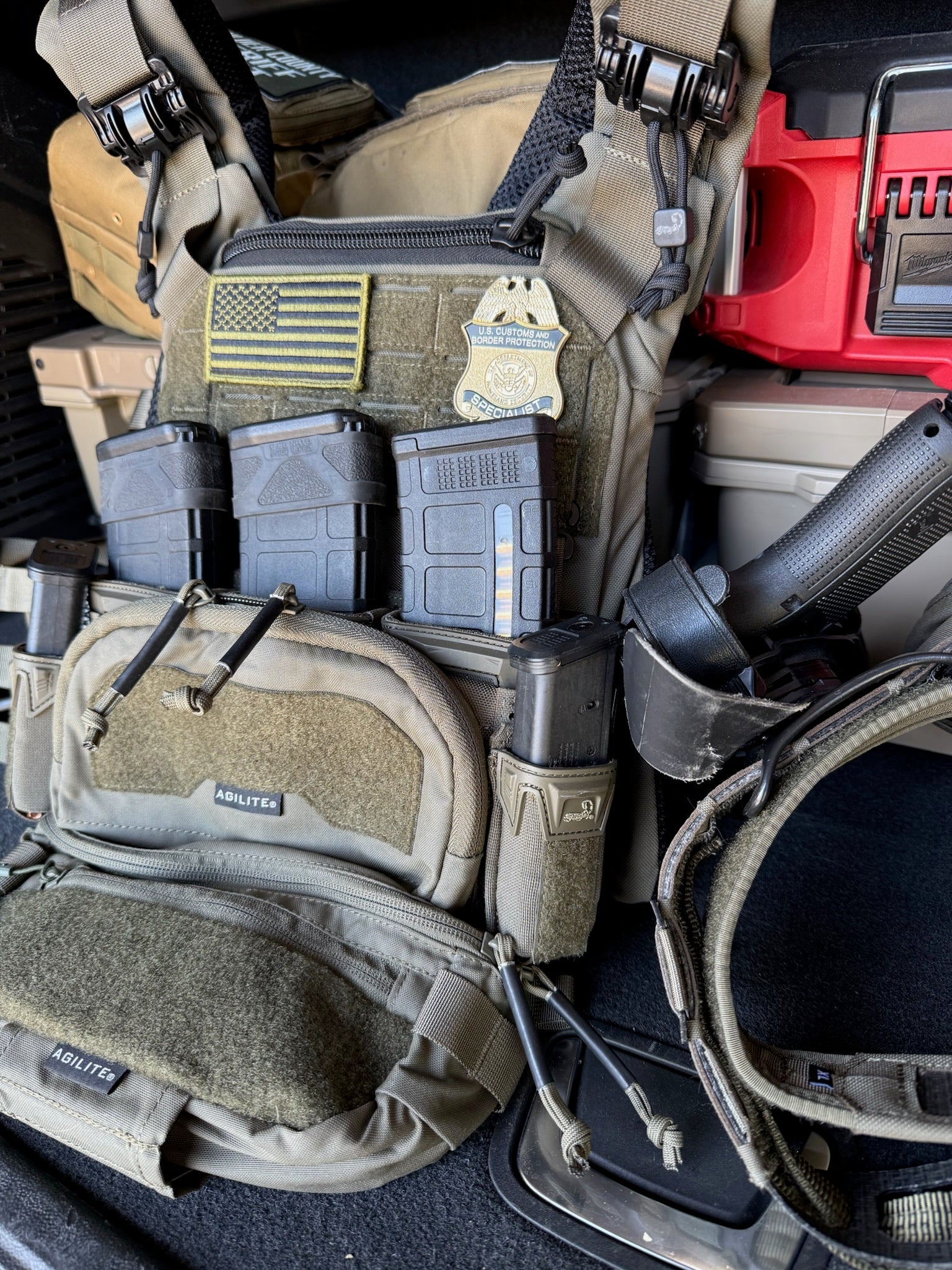 Tactical gear including a vest with a flex badge and pouches, and ammunition in a vehicle.
