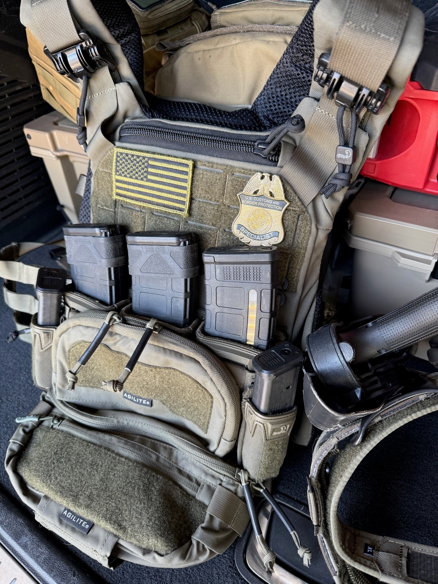 Tactical vest with CBP flex badge and various pouches and equipment inside a vehicle