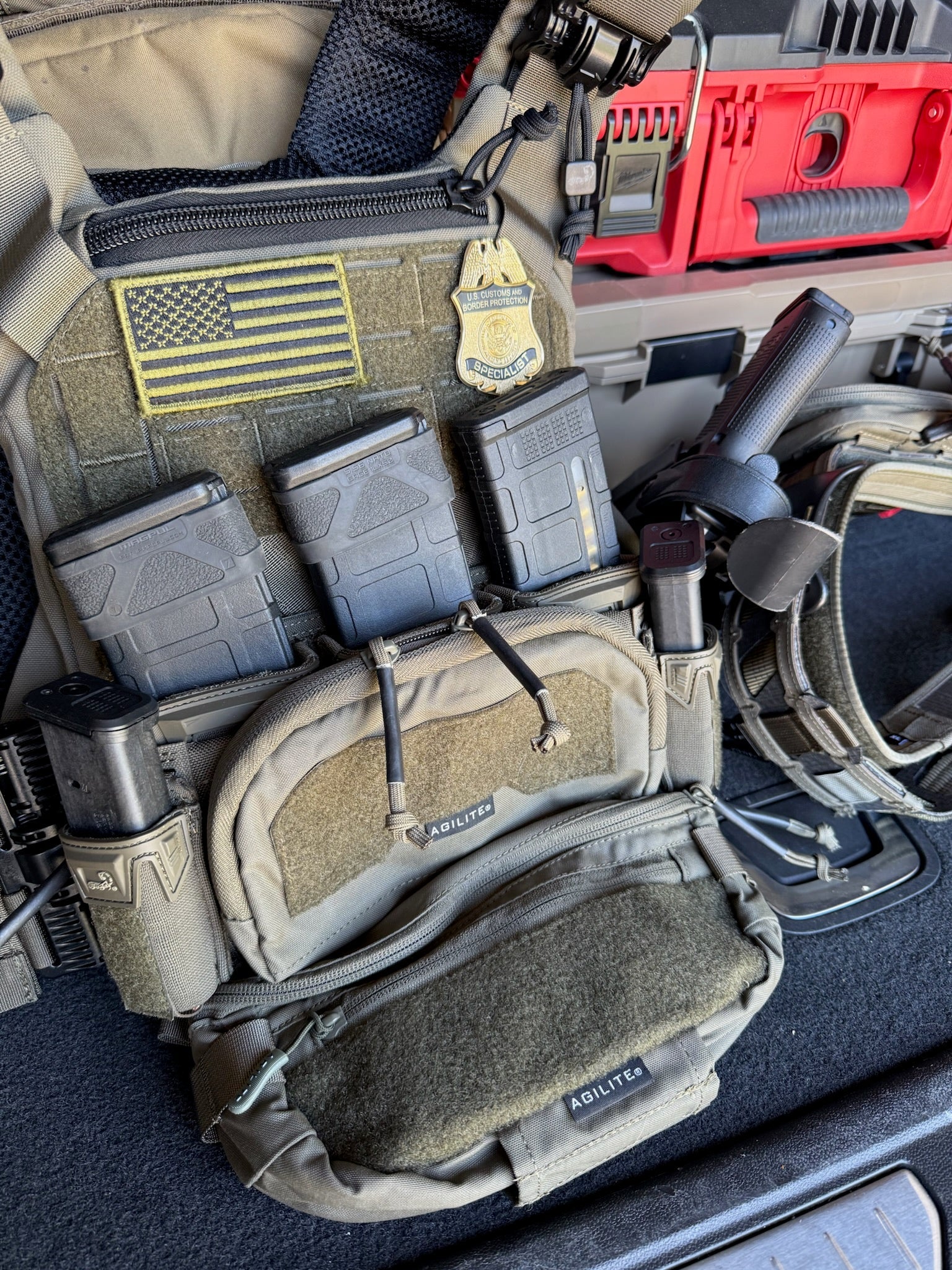 Tactical vest with flex badge and various pouches and equipment inside a vehicle