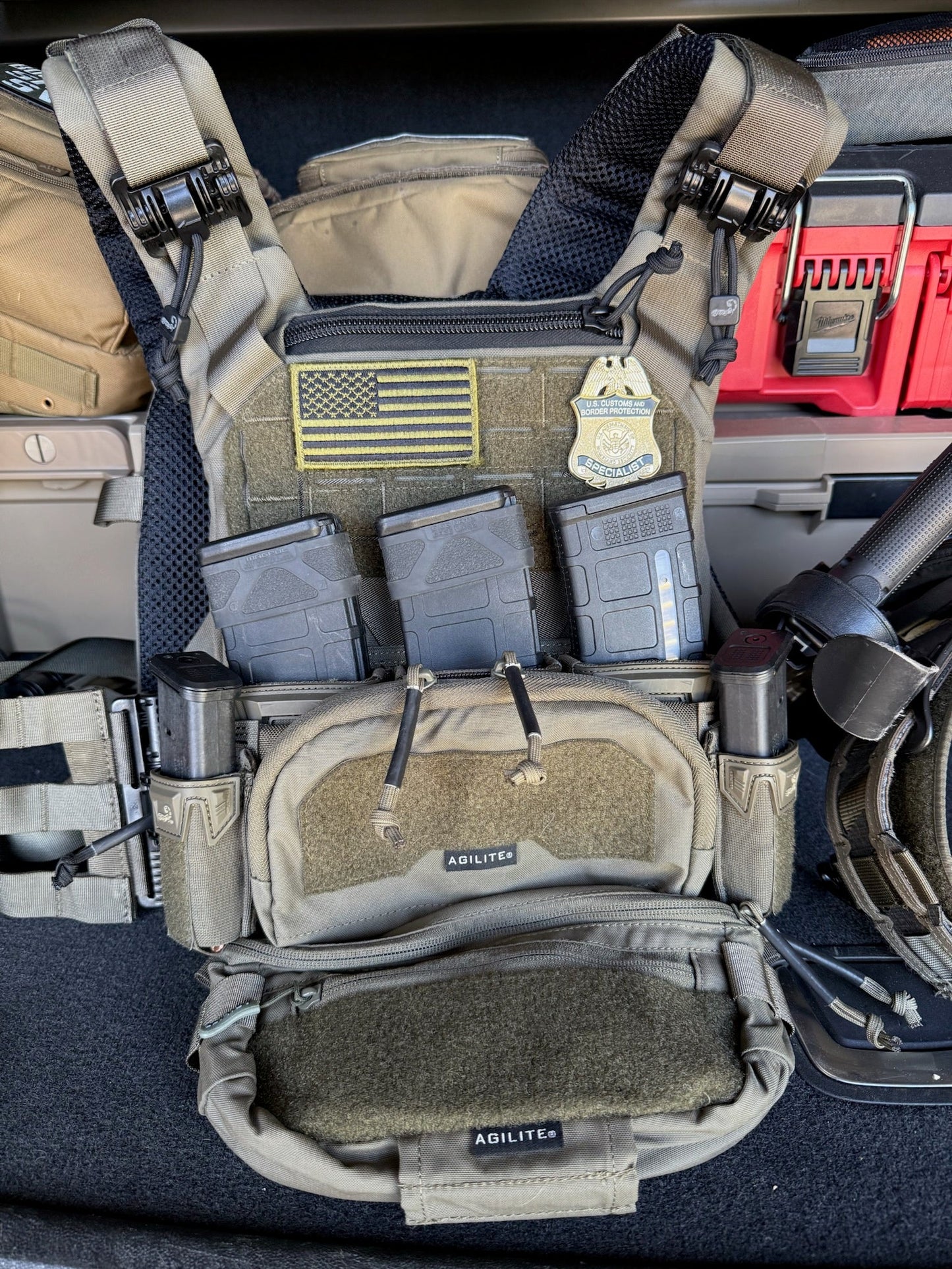 Tactical vest with Flex Badge patch and flag patch and multiple pouches on a vehicle seat.