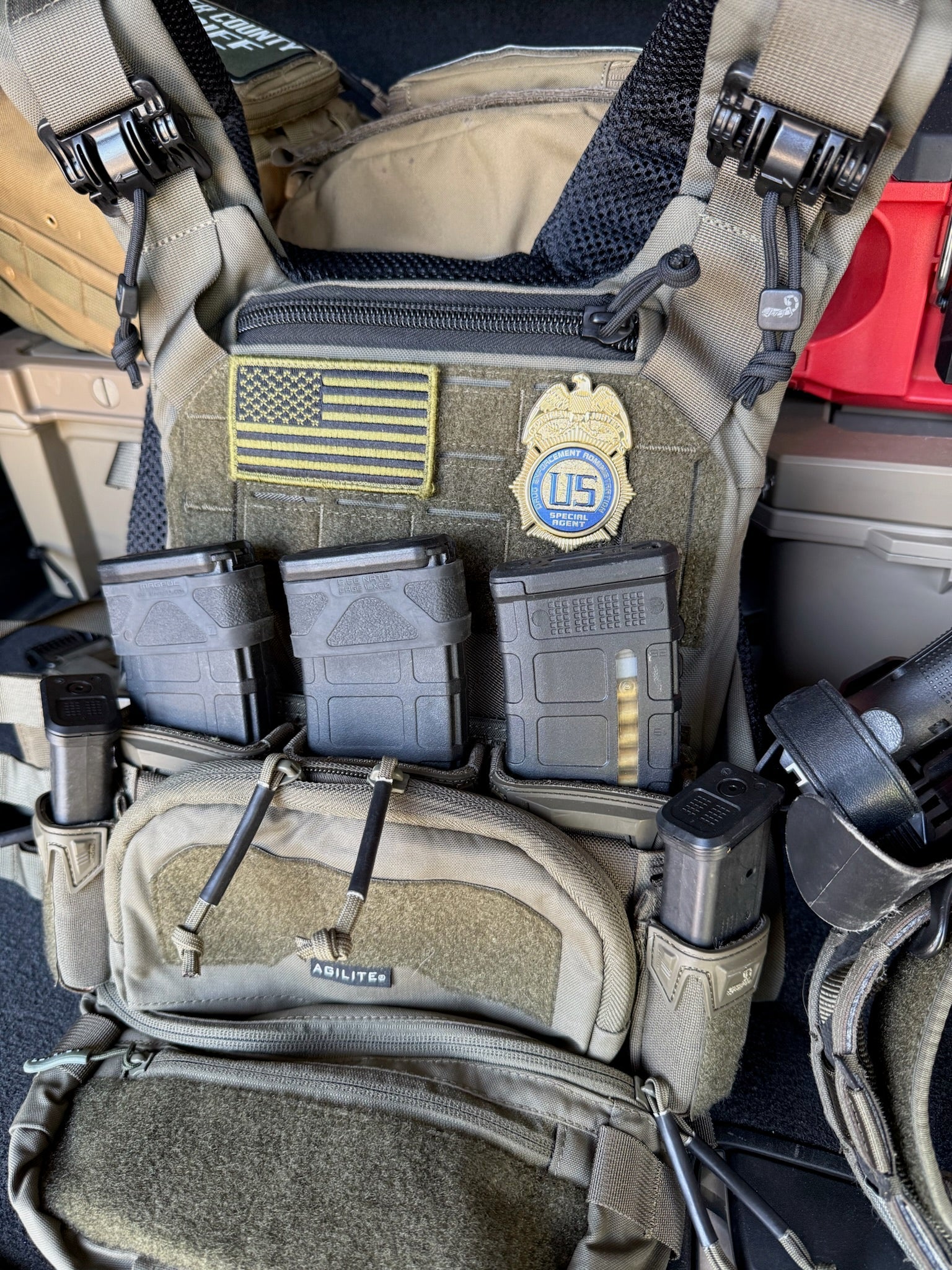 Tactical vest with DEA Flex Badge,  American flag patch, and U.S. emblem.