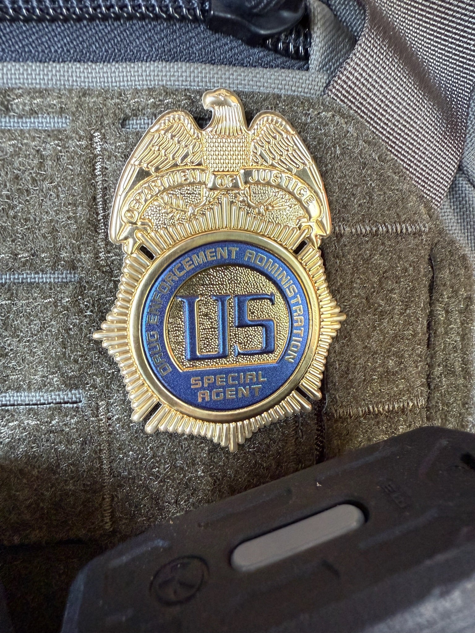 Gold and blue DEA Special Agent Flex badge on a tactical pouch