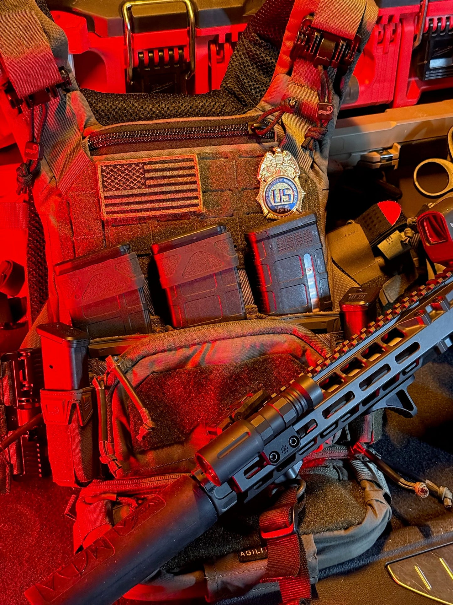 Close-up of tactical gear with a rifle, American flag patch, and DEA flex shield badge patch. 